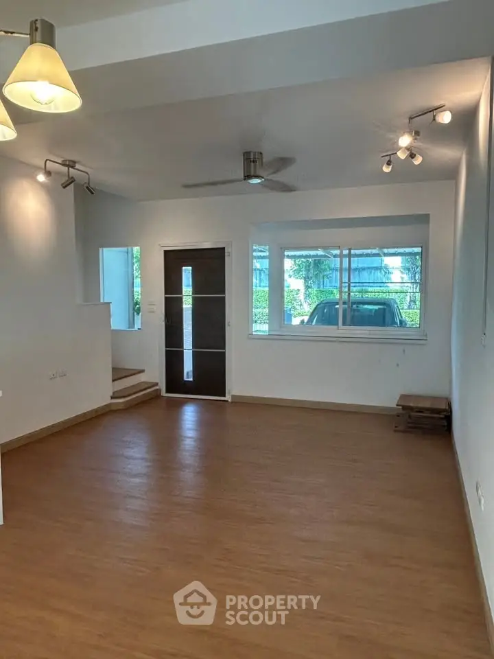 Spacious living room with wooden flooring and modern lighting in a bright home.