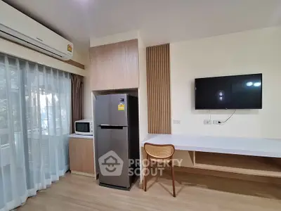 Modern apartment interior with fridge, microwave, and wall-mounted TV in a stylish living space.