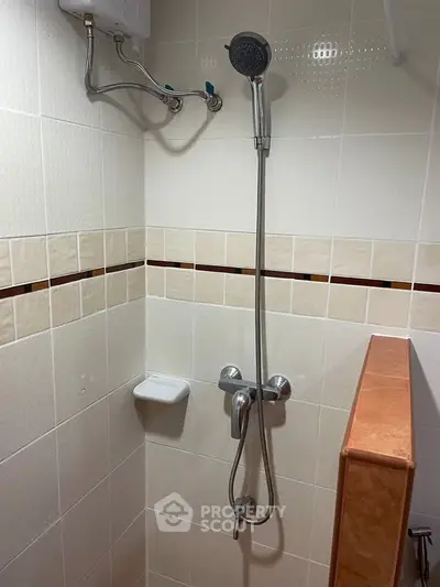 Compact bathroom shower area with modern fixtures and tiled walls.