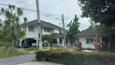 Charming suburban house with lush greenery and traditional spirit house in the garden.