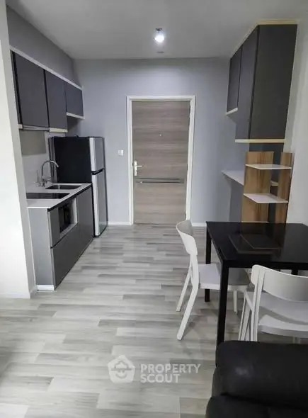 Modern kitchen with sleek cabinets and dining area in stylish apartment.