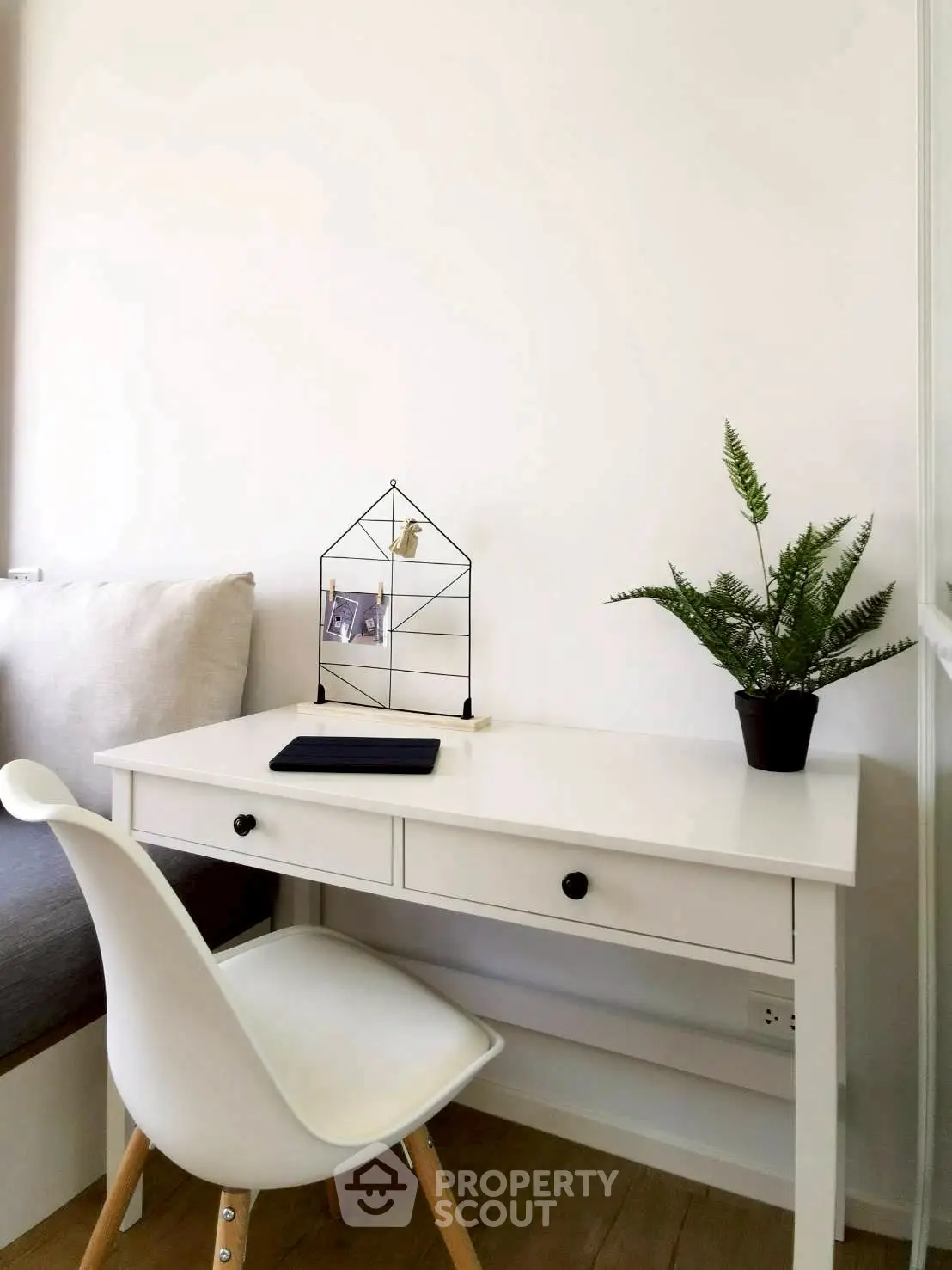 Modern study nook with white desk, chair, and plant for a cozy workspace.