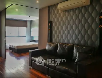Modern living room with stylish black leather sofa and adjacent bedroom