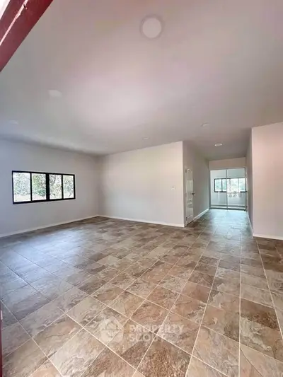 Spacious open-plan living area with tiled flooring and large windows for natural light.