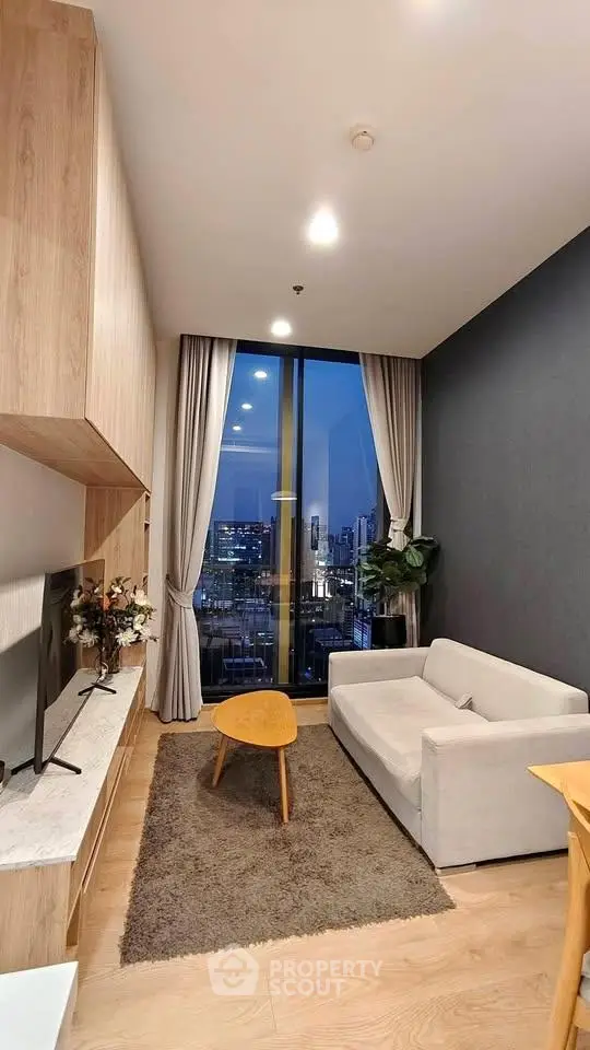 Modern living room with city view, cozy sofa, and stylish decor in high-rise apartment.