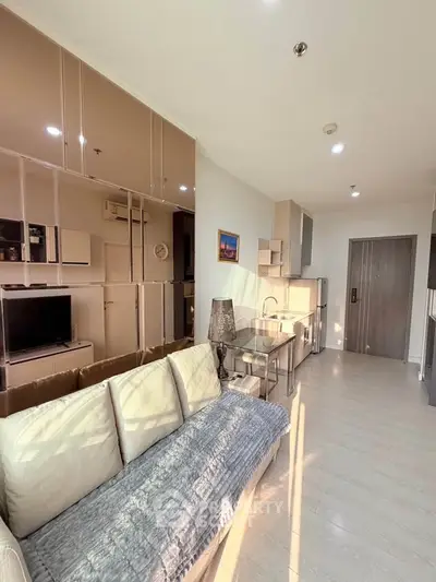 Modern living room with sleek design and natural light, featuring a cozy sofa and stylish kitchen area.