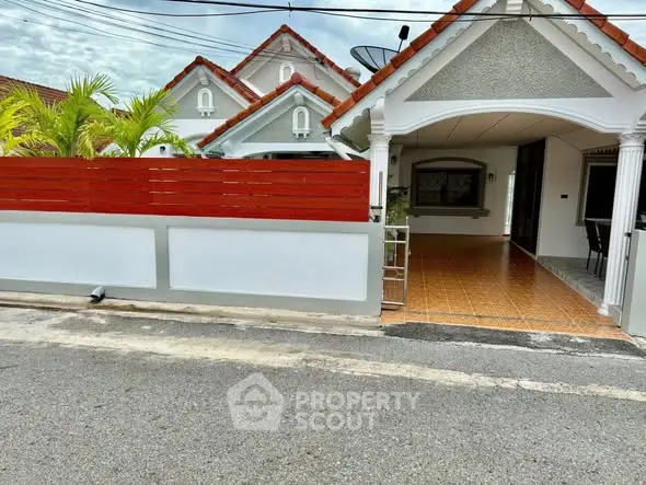 Charming suburban house with red roof and spacious driveway, perfect for family living.