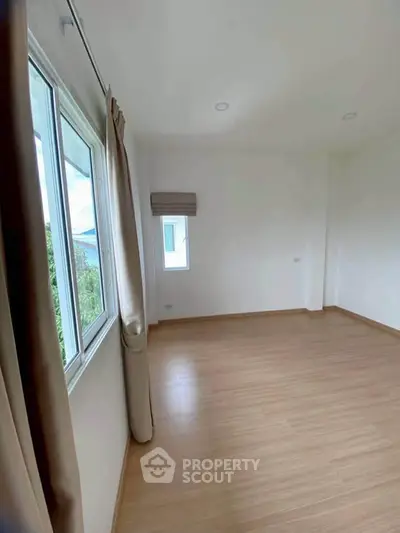 Spacious empty room with large windows and wooden flooring, perfect for customization.
