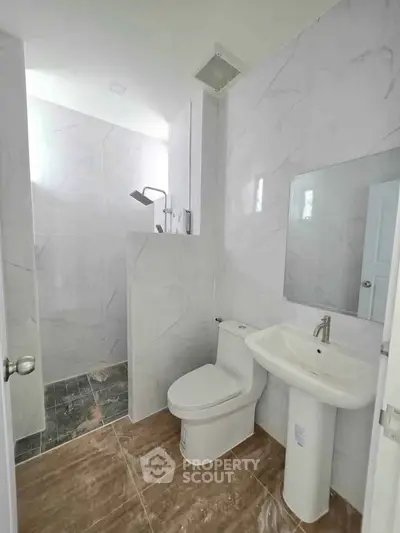 Modern bathroom with sleek fixtures and marble tiles, featuring a spacious shower area.