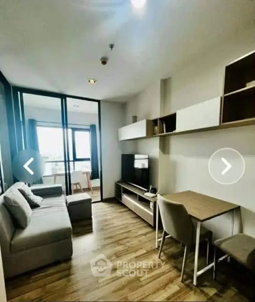 Modern living room with stylish furniture and wooden flooring, featuring a cozy sofa and a sleek TV unit.