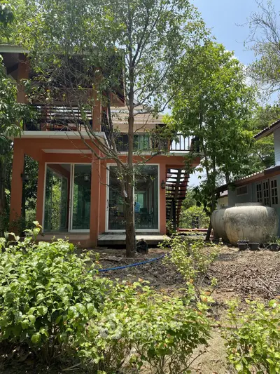 Charming two-story home with lush garden and large windows in tranquil setting