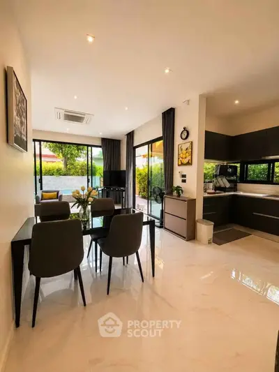 Modern open-plan living room and kitchen with elegant dining area and large windows.