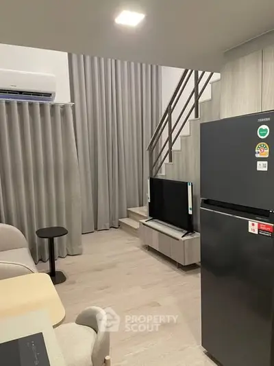 Modern duplex living room with sleek design and staircase, featuring air conditioning and stylish furniture.