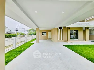 Spacious modern home entrance with covered driveway and lush green lawn