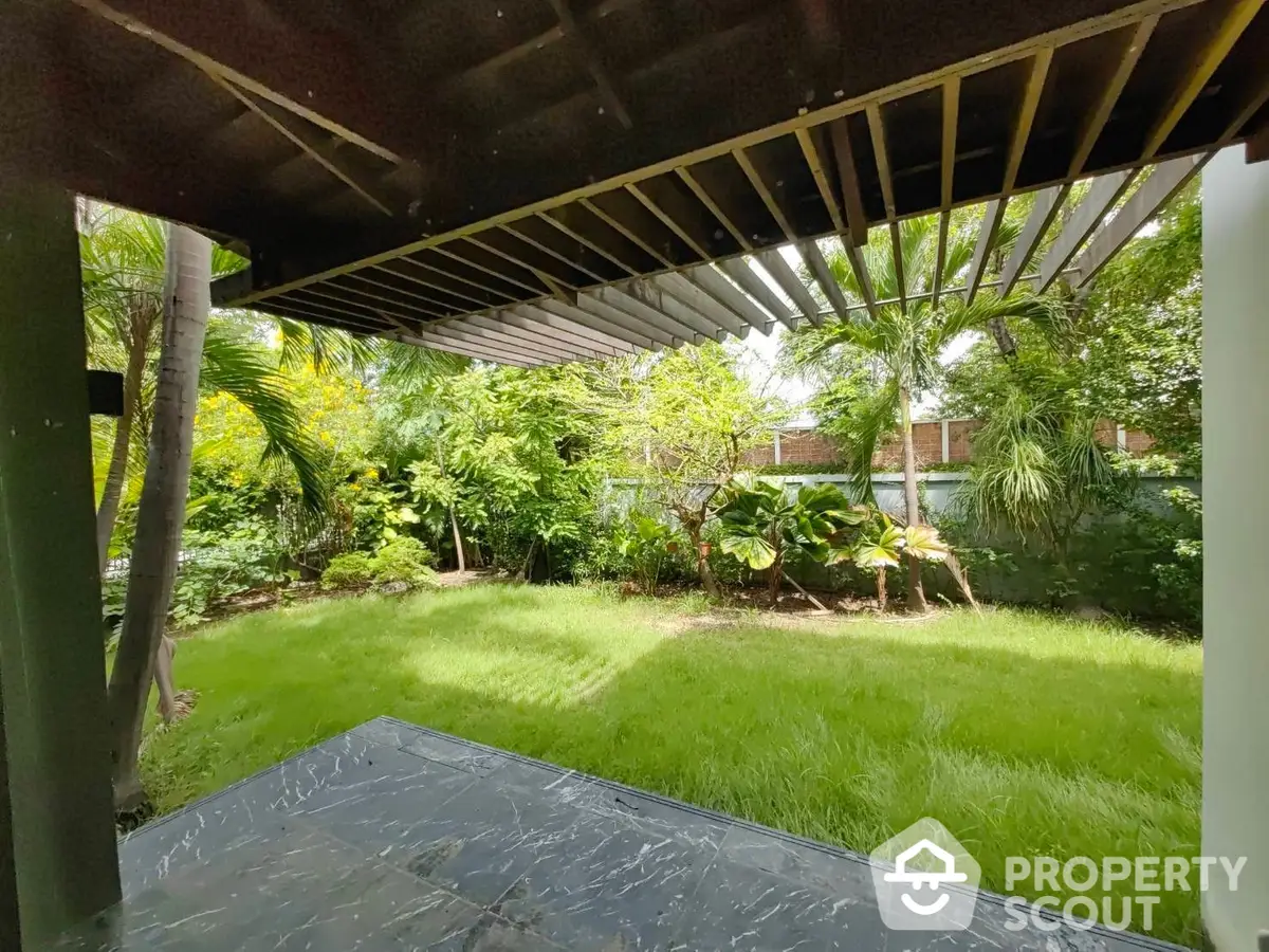 Lush green garden viewed from a shaded patio area, offering a serene outdoor living space perfect for relaxation and entertainment.