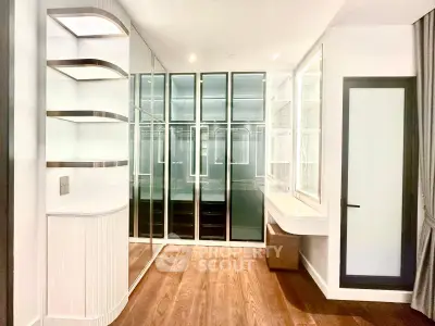 Luxurious walk-in closet with mirrored doors and elegant shelving in modern apartment.