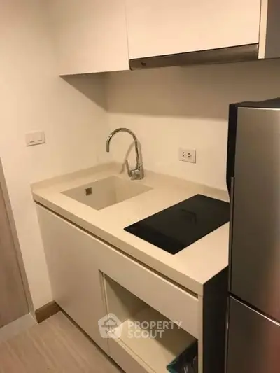 Modern compact kitchen with sleek design and built-in appliances in a contemporary apartment.