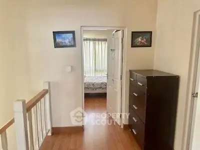 Charming interior hallway leading to a cozy bedroom with natural light and wooden flooring.
