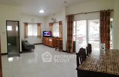 Spacious living room with tiled floor and dining area, featuring large windows and natural light.
