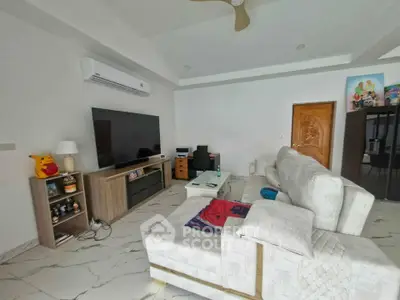 Spacious modern living room with sleek furniture and large TV, perfect for relaxation and entertainment.