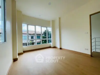 Spacious empty room with large windows and wooden flooring, offering a bright and airy atmosphere.