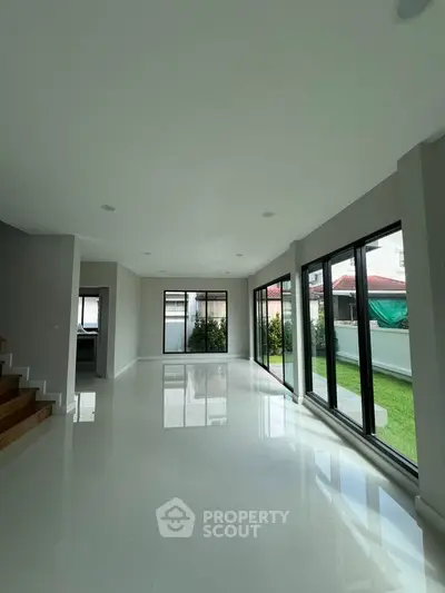 Spacious modern living room with large windows and garden view, perfect for natural light lovers.