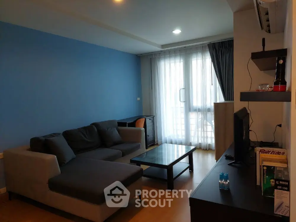 Modern living room with blue accent wall, cozy sofa, and natural light from large window.