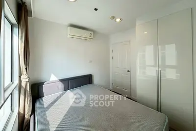 Bright bedroom with large window, modern air conditioning, and sleek wardrobe in a stylish apartment.