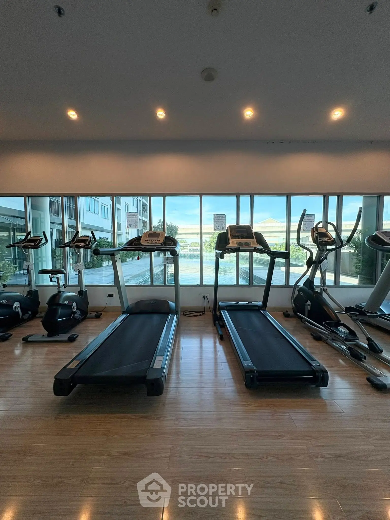 Modern gym with treadmills and exercise bikes overlooking a scenic view, perfect for fitness enthusiasts.