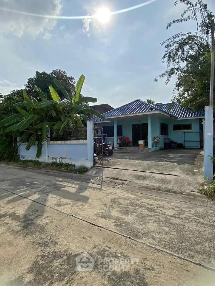 Charming single-story home with blue accents and lush greenery, perfect for serene living.