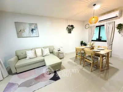 Modern living room with stylish decor and dining area, featuring a cozy sofa and elegant lighting.