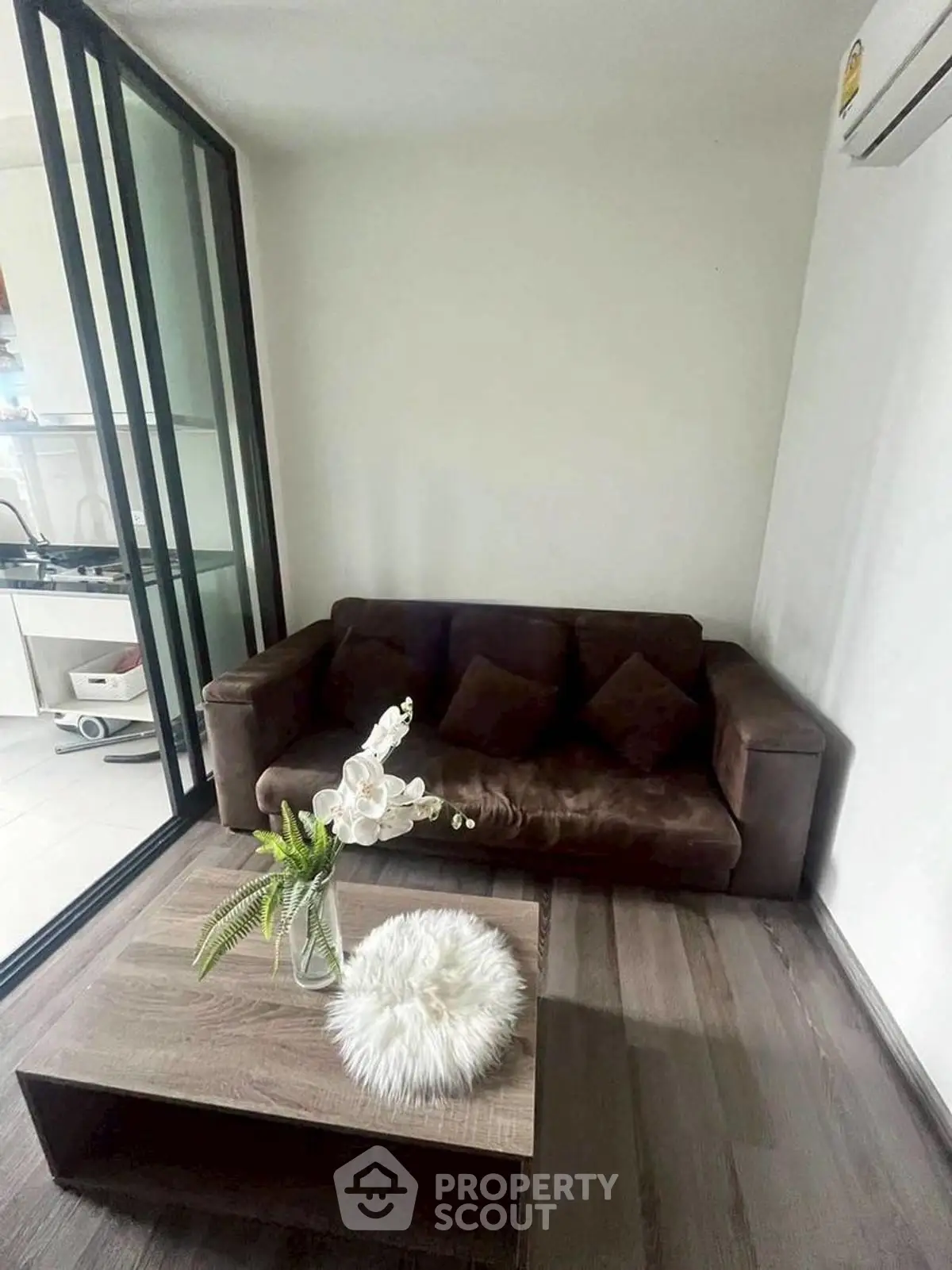 Cozy living room with brown sofa and modern decor, adjacent to sleek kitchen area.