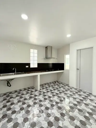 Modern kitchen with sleek black and white design, featuring geometric floor tiles and ample counter space.