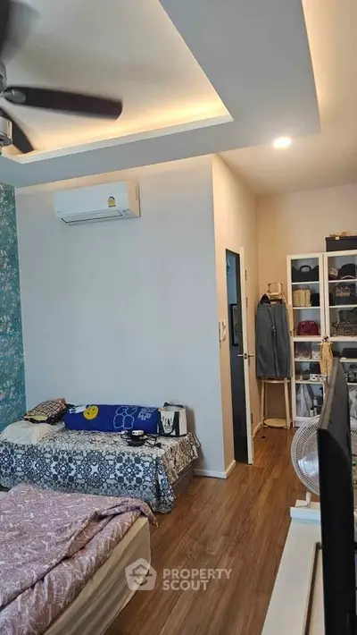 Cozy bedroom with modern decor, featuring wooden flooring and ample storage space.