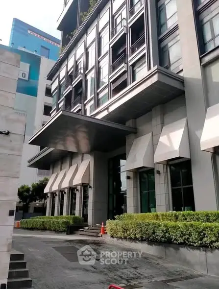 Modern building exterior with sleek design and lush greenery, showcasing urban sophistication and architectural elegance.