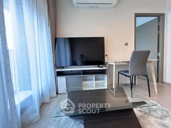 Modern living room with sleek TV, glass coffee table, and cozy seating area.