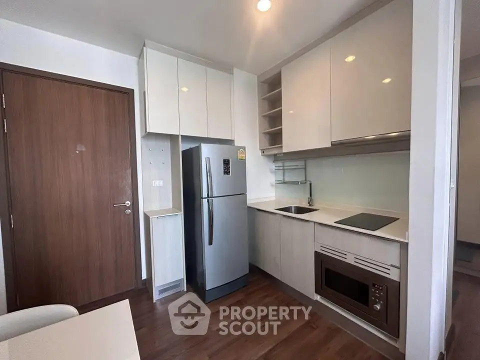 Modern kitchen with sleek cabinets, stainless steel fridge, and built-in appliances in a stylish apartment.