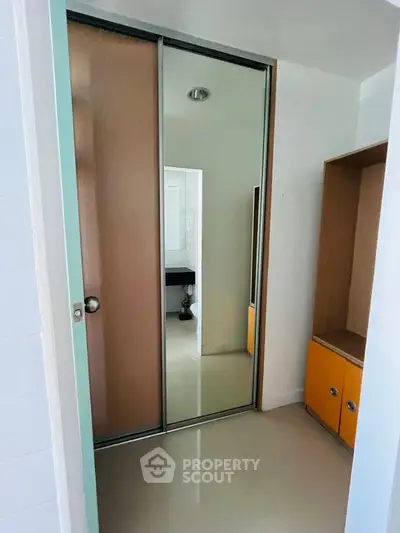 Modern bathroom with sliding mirror door and sleek storage cabinets.