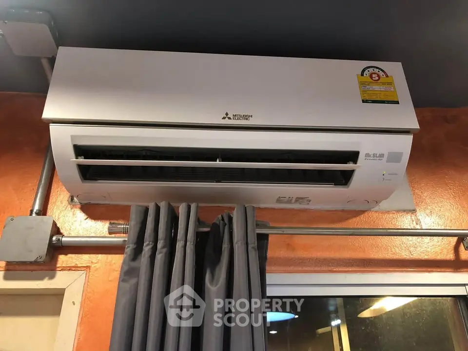 Modern air conditioning unit installed above window with stylish curtains in a cozy room.