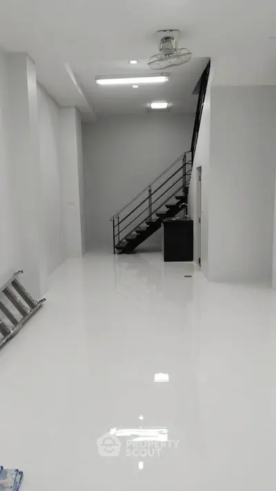 Spacious modern interior with sleek staircase and glossy white flooring, ideal for contemporary living.