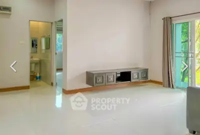 Spacious living room with modern TV console and balcony access