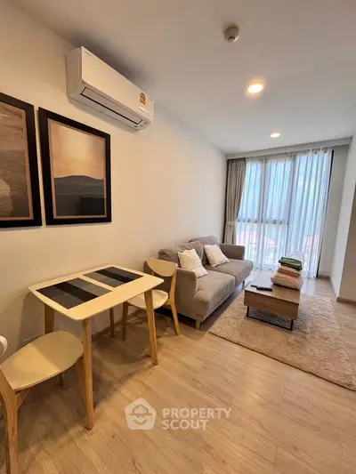 Modern living room with cozy sofa, dining table, and large window for natural light.