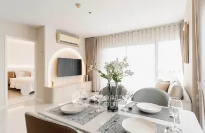 Modern living room with dining area, featuring elegant decor and natural light, adjacent to a cozy bedroom.