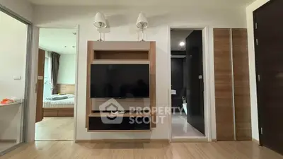 Modern apartment interior with wall-mounted TV and view into bedroom and bathroom.