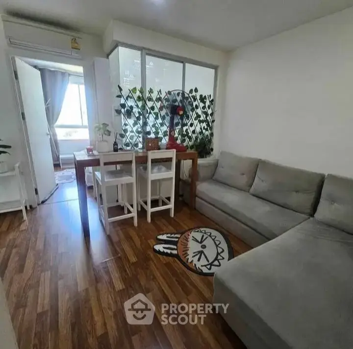 Cozy living room with modern decor and wooden flooring, featuring a comfortable sofa and dining area.