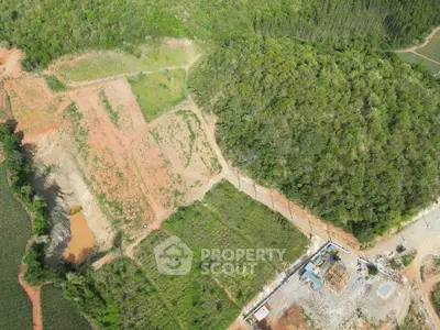 Aerial view of a lush green landscape with a construction site, showcasing potential for real estate development.