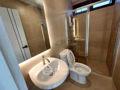 Modern bathroom with sleek fixtures and glass shower enclosure in a contemporary home.