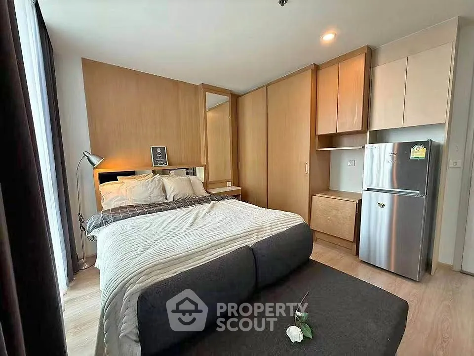 Modern bedroom with cozy bed and compact kitchen area in stylish apartment.