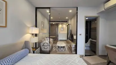 Modern studio apartment with glass partition, cozy bedroom, and stylish living area.