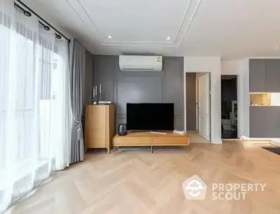 Spacious living room with modern design, herringbone parquet flooring, and an open layout leading to a sleek kitchen.